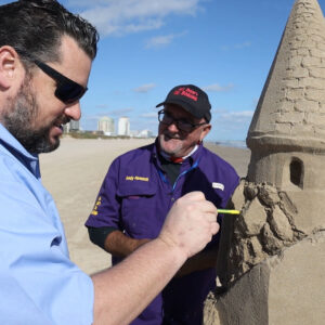 Andy Hancock teaching celebrity shane from the texas bucket list tv show how tom detail a sandcastle