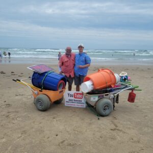 Andy Hancock with a former instructor on south padre island beach behind two fully loaded tool carts containing all the equipment required for a sandcastle lesson with science.