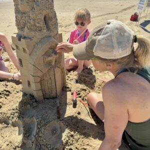 A family of 4 during a 2 hour sandcastle lesson working on the main tower together