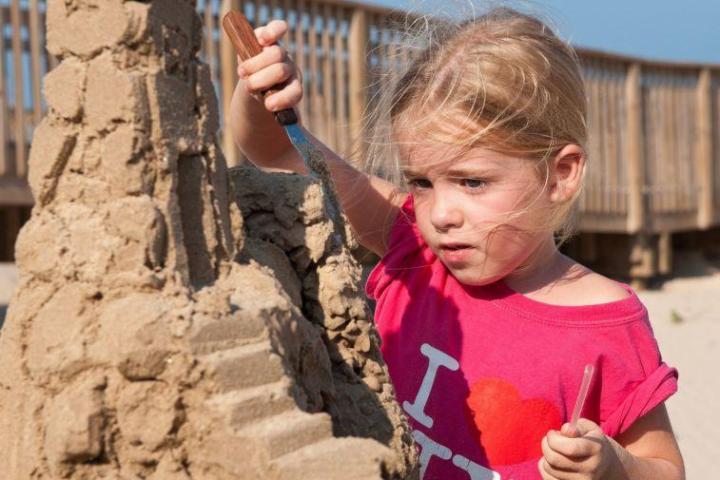 a little girl standing in front of a brick building